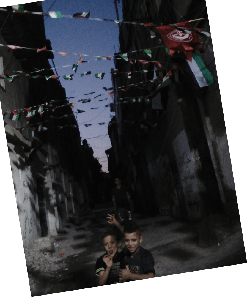 two children making faces under Palestine's flag in alley 